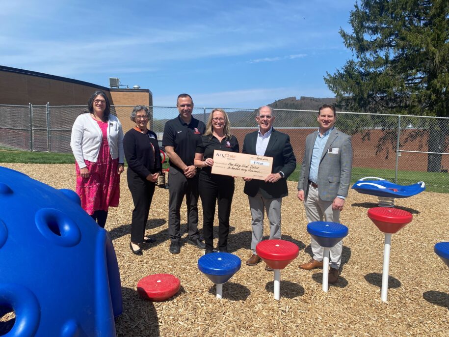 Group standing with $100,000 check in playground